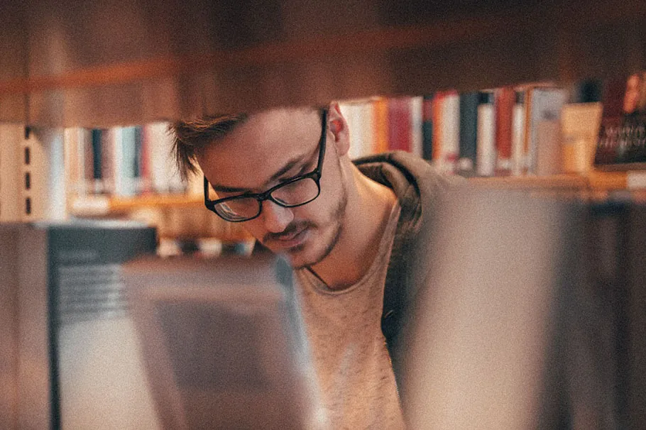 A person looking at a shelf full of books.
