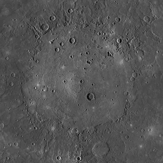 Photograph of the Caloris Basin on Mercury. The circular, flat plain of Caloris Basin is surrounded by cratered highlands and rough terrain. A few impact craters are scattered over the smooth surface of the basin.