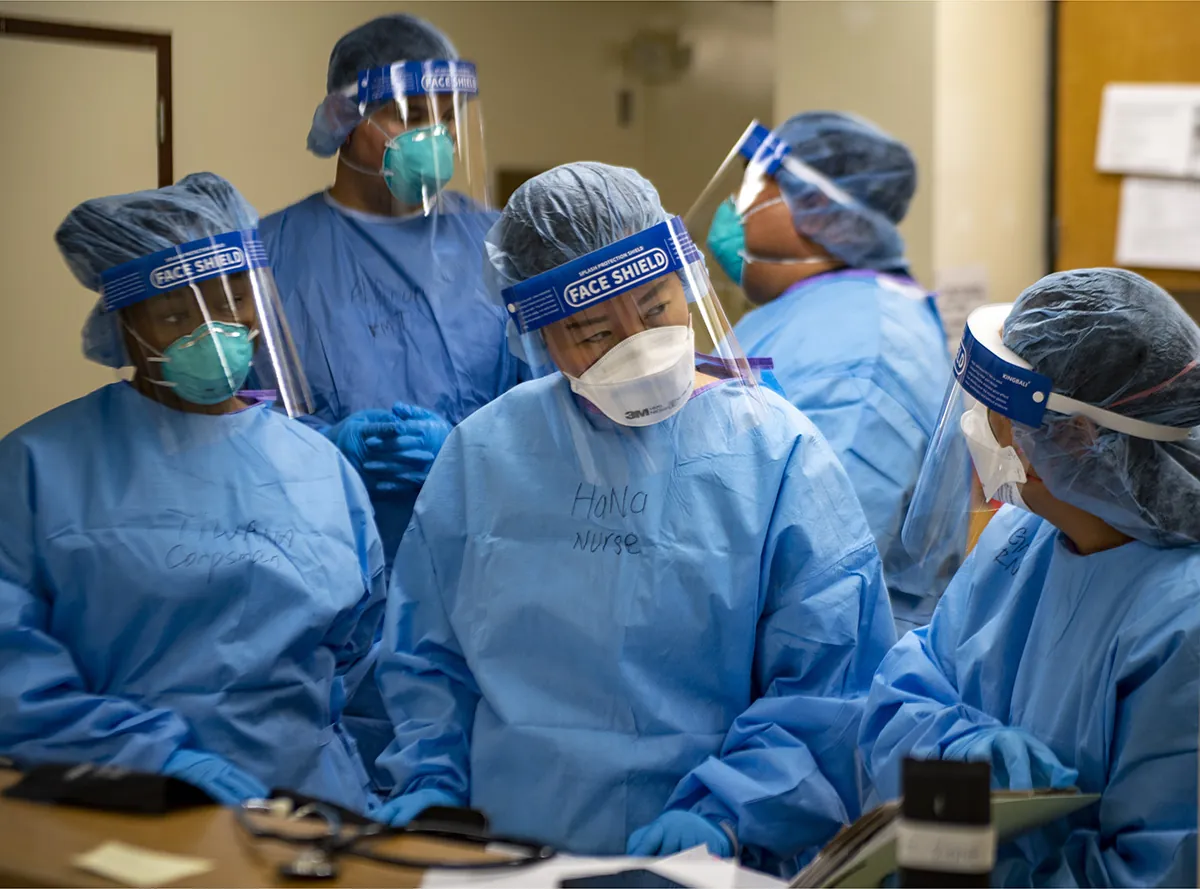 A color photograph shows a group of five medical workers in protective gear.