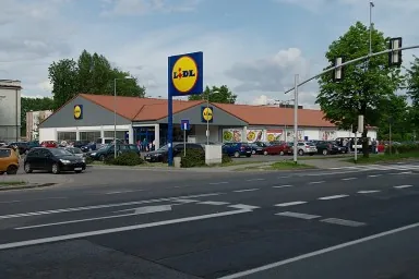 A Sonic drive thru is shown. The Sonic logo appears on the top center of the building; menus are posted near the curbs of the drive thru lane.