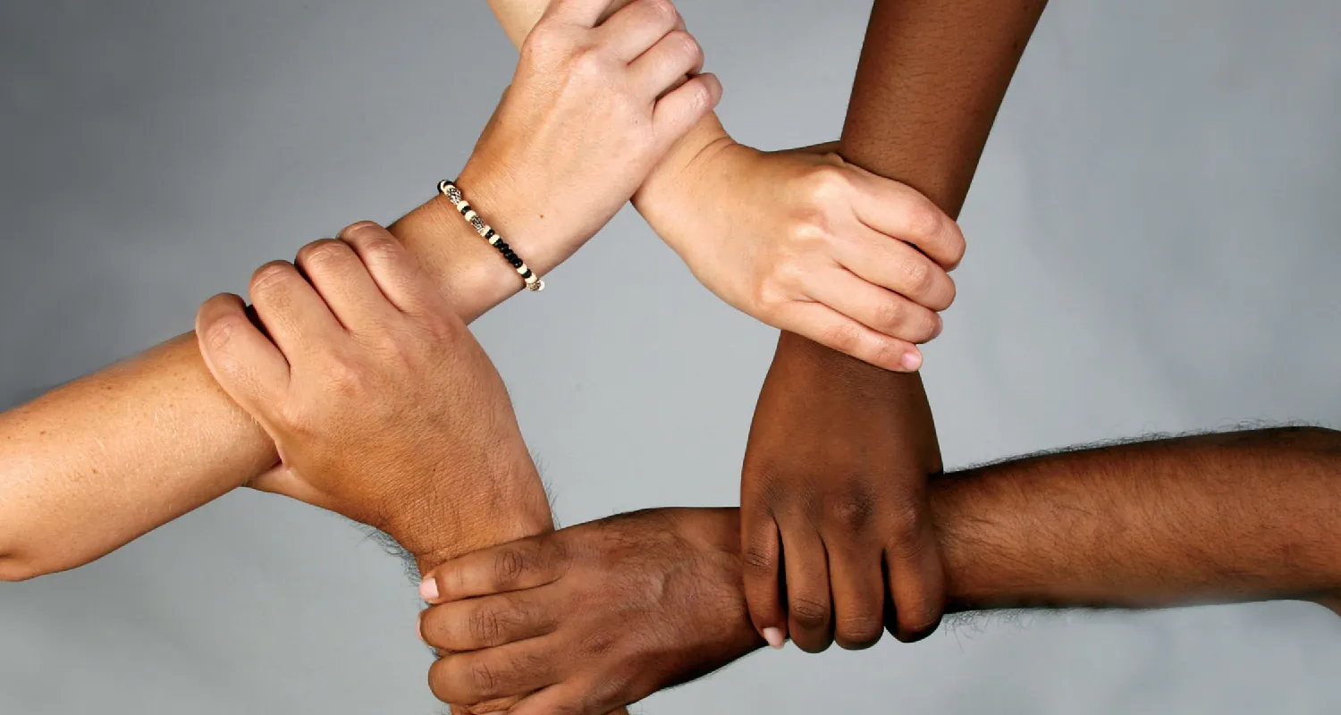 Flickr, A photo of four arms, all with different skin tones, linked by hands at the wrists to form a square.