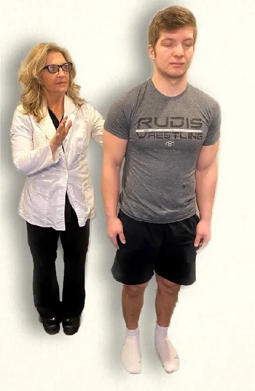 A nurse hold their hands up behind a standing patient during a Romberg test.