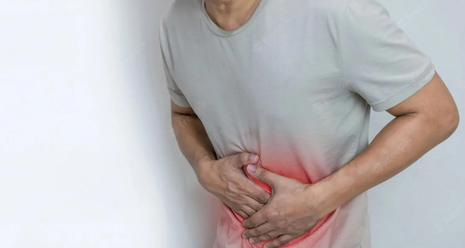 Person holding stomach with red coloring on stomach.