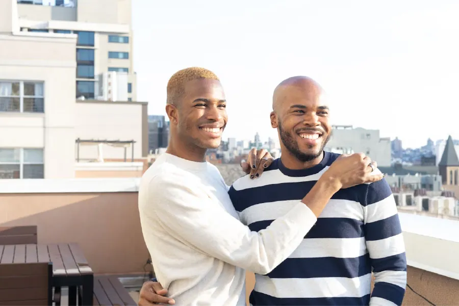 Photo of two young adults holding each other and smiling.