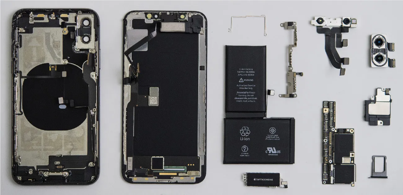 An iPhone taken apart and separated into about ten parts. Visible are the battery, the haptic engine, the camera, and the larger frames.