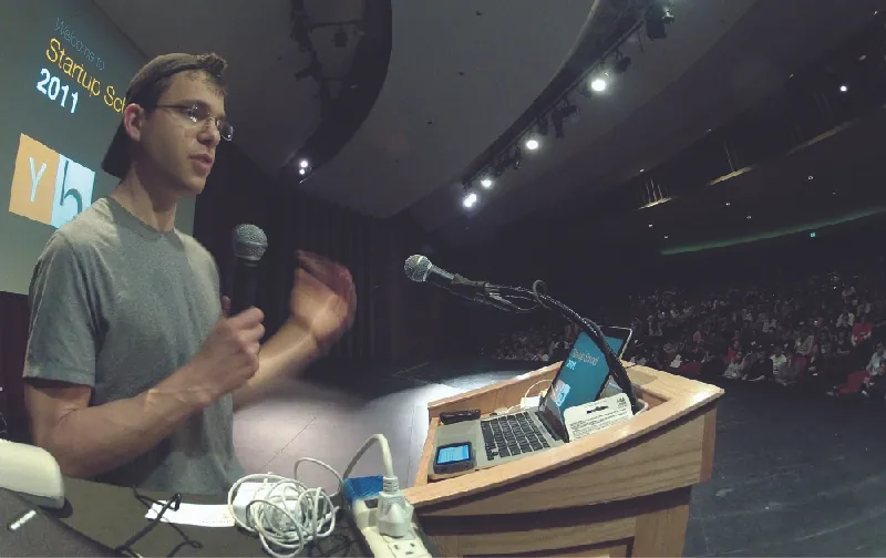 A photograph shows a person speaking to a crowd from a podium.