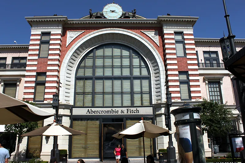 The facade of a three-story brick building is shown. Taking up most of the second and third story is an arch that is filled in with windows. The Abercrombie and Fitch logo is below the windows, and the door is below the logo.