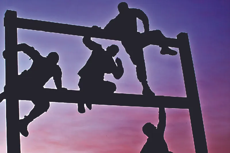 Photo of people climbing a tall barrier.