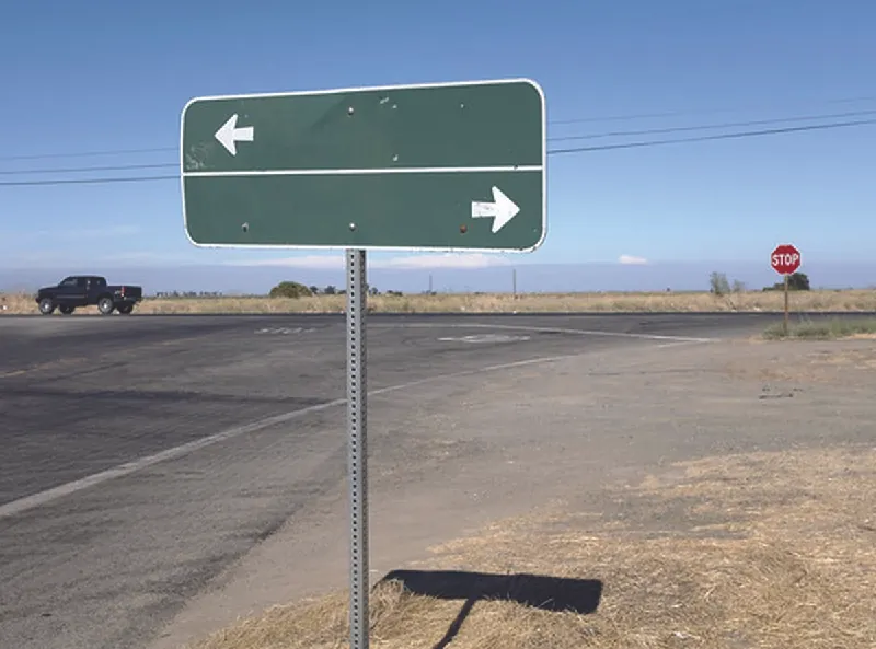 Road sign with arrows pointing in opposite directions.