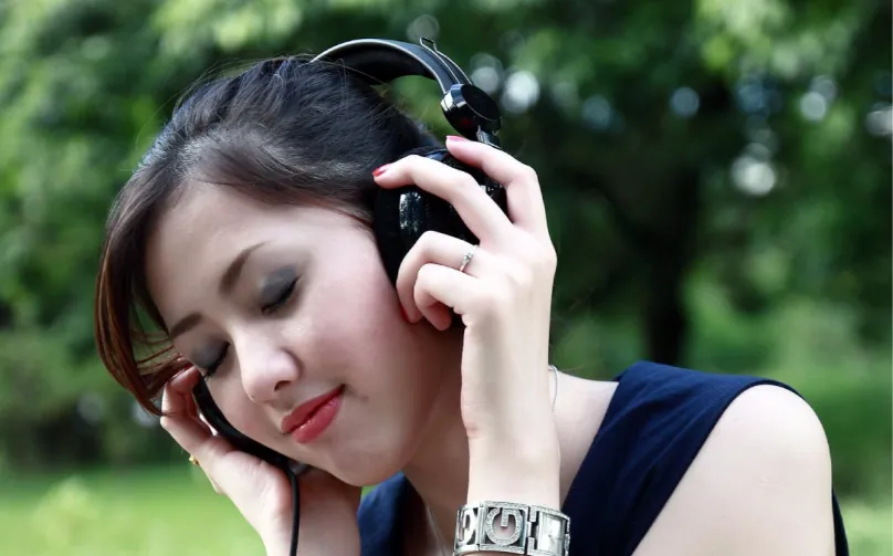 Photo of person wearing headphones, eyes closed, and smiling.