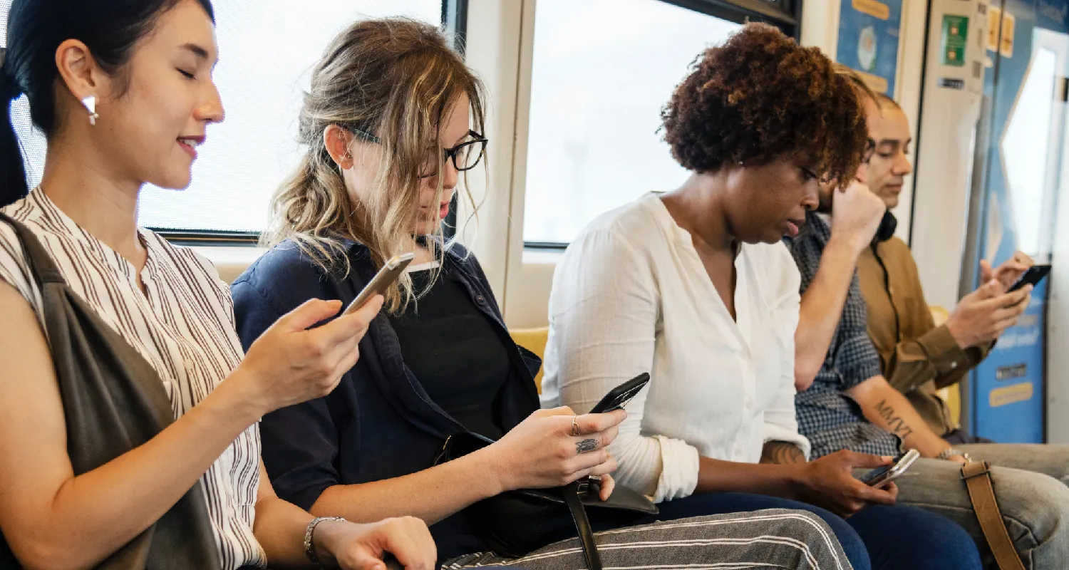 Photo of five young and middle aged adults sitting and interacting with their cell phones.