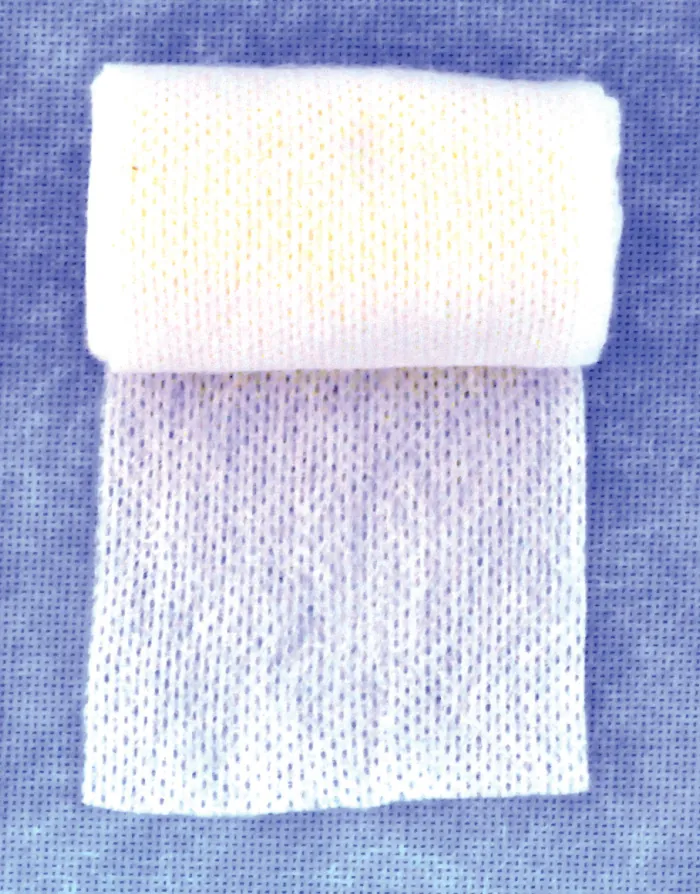 A folded strip of white, porous, non-woven fabric, possibly medical gauze, rests on a blue textured background, showcasing its fine mesh structure and soft appearance.