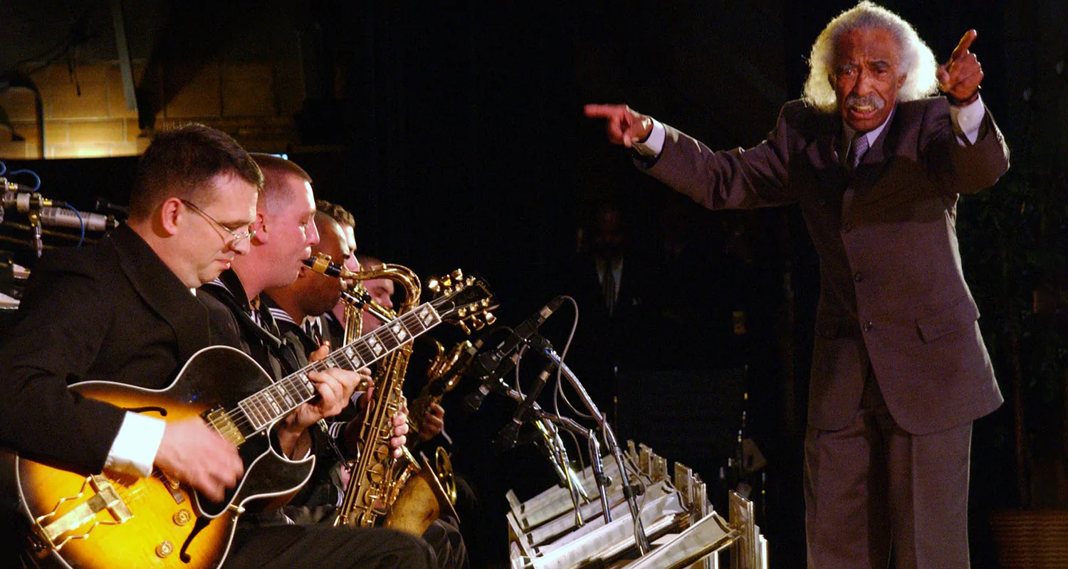 The photo of a conductor leading a group of musicians.