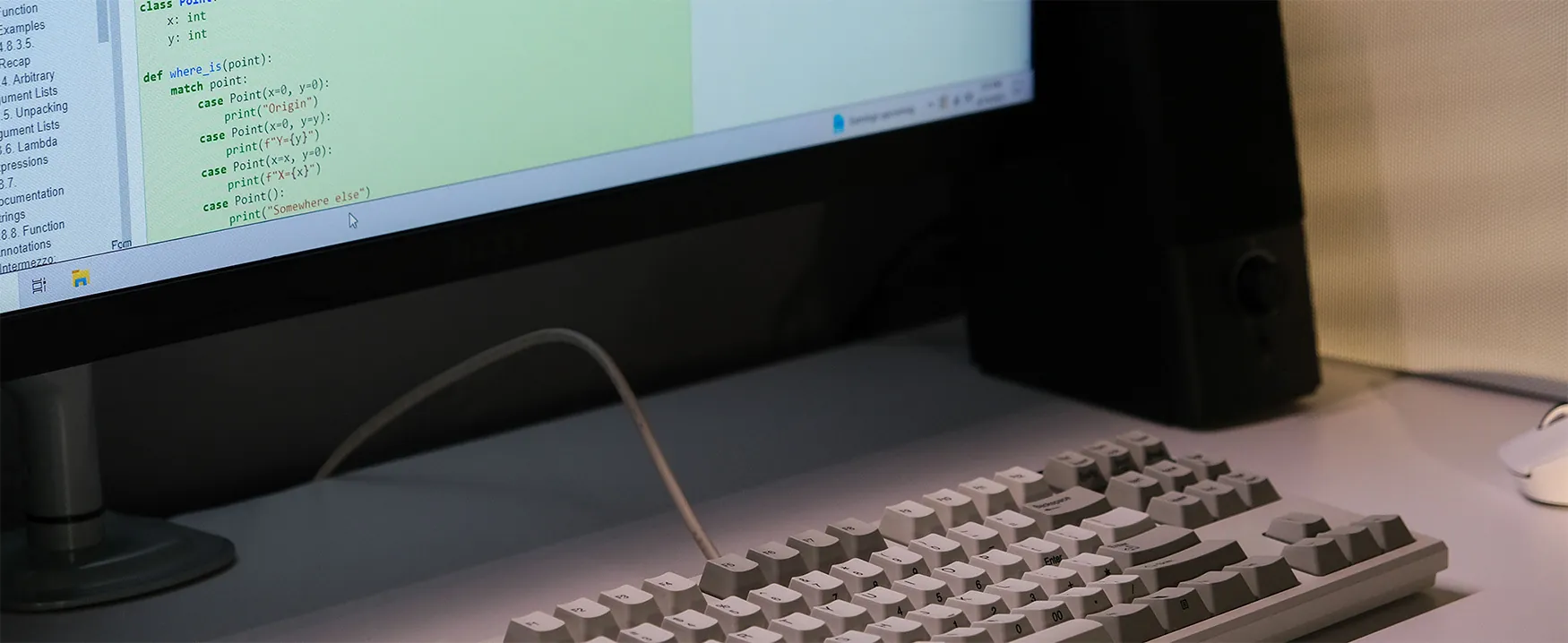 Photo of a mechanical keyboard and a computer screen, with part of the Python specification document shown on the screen.