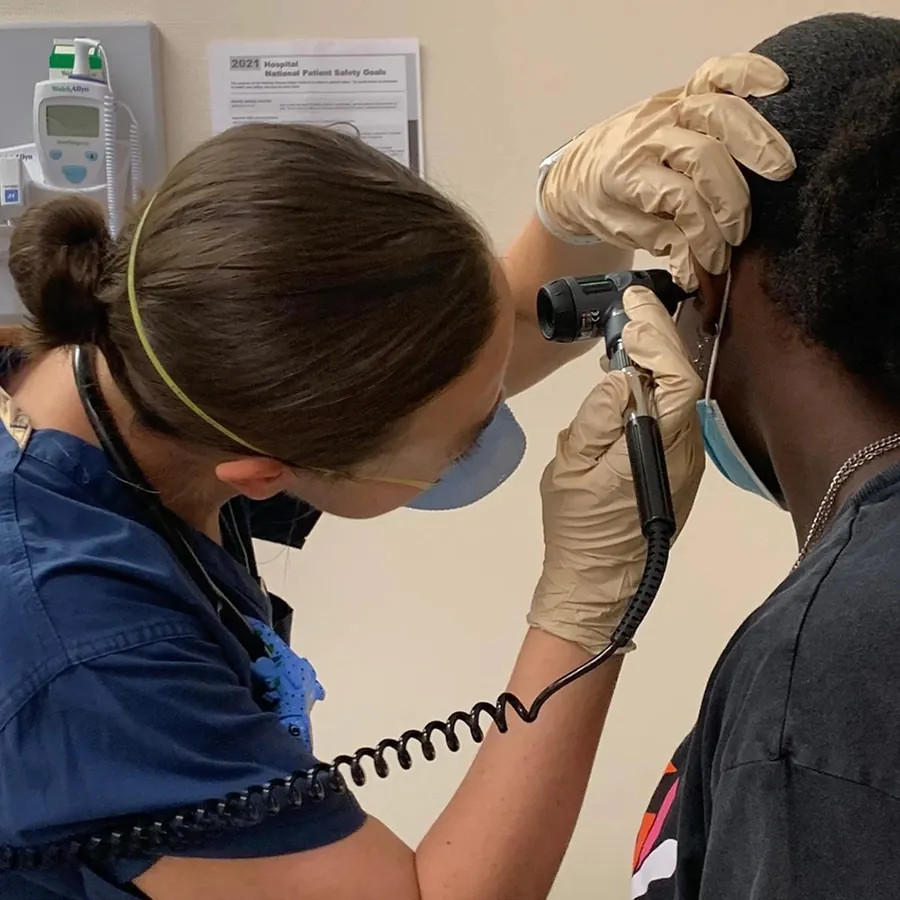 A photo of a provider using a device to examine a patient’s ear.