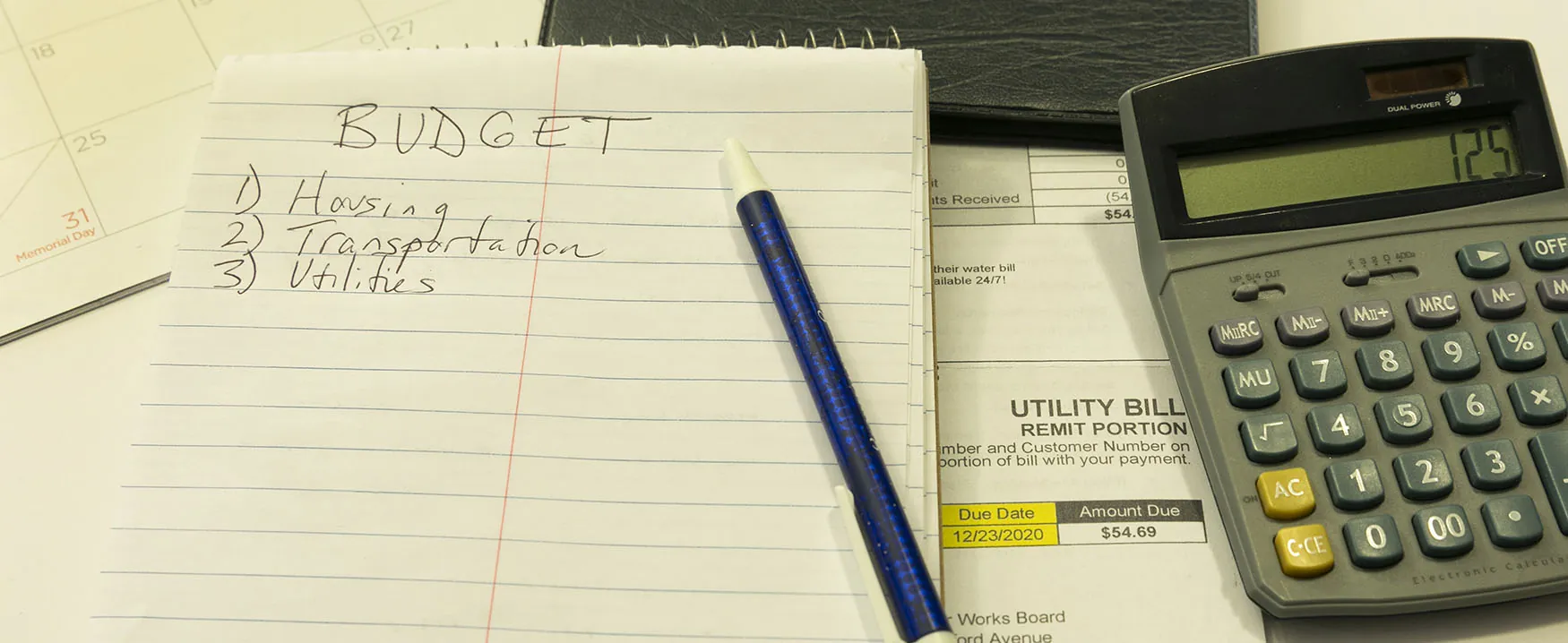 A photo of a notepad and a pen. The notepad says "Budget" across the top, with a numbered list below…