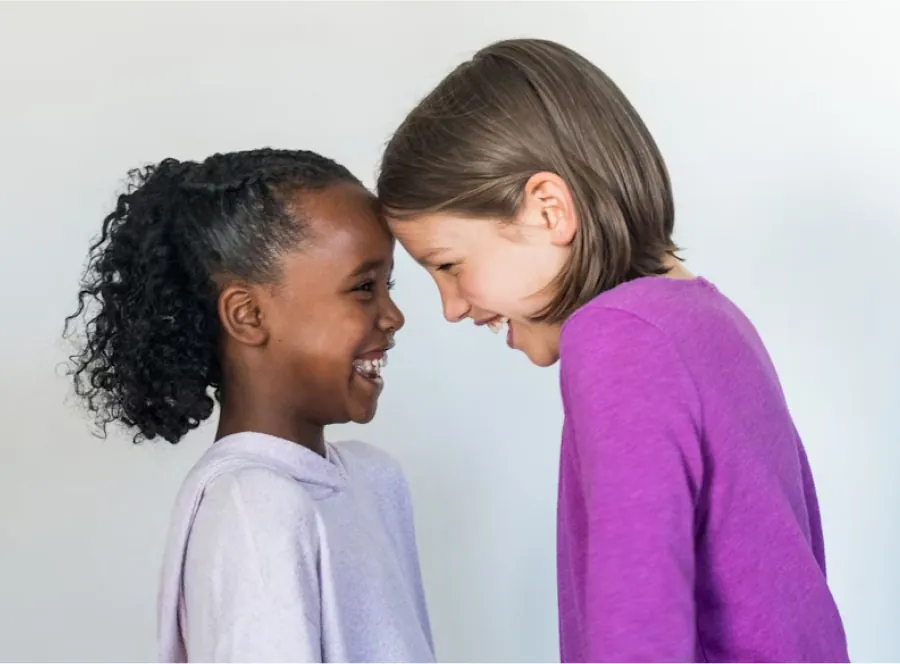 Photo of two young children laughing, their foreheads touching.