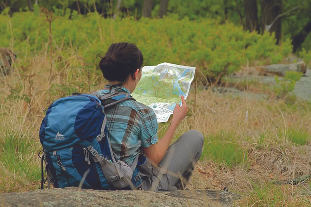 Photo of a person reading a map while sitting in a field.