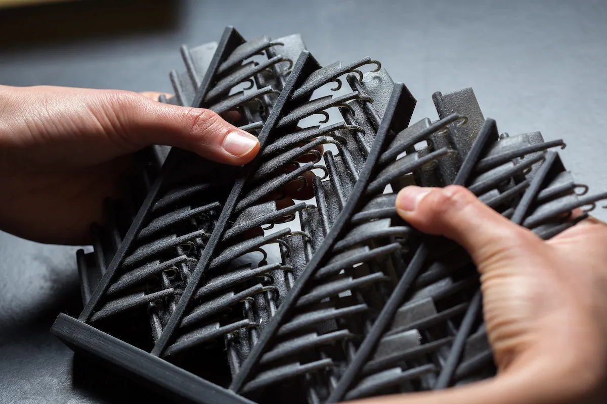 Hands hold large artificial feathers, which include the central barb, the and the smaller offshooting barbules. At the end of each barbule is a thinner hook structure. 