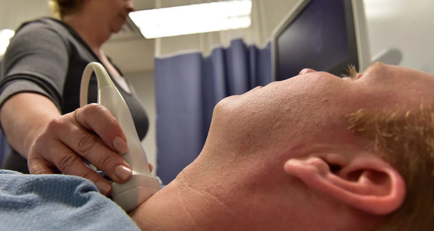 Photo of healthcare worker doing an ultrasound on an individual’s throat.
