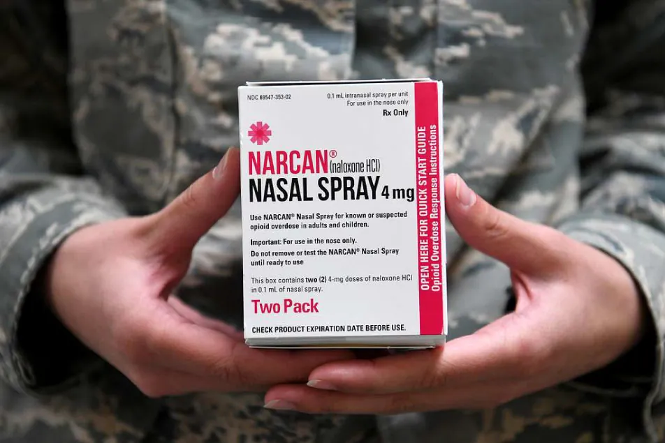 Photo of individual holding box of Narcan (naloxone HCl) Nasal Spray 4 mg (two pack).