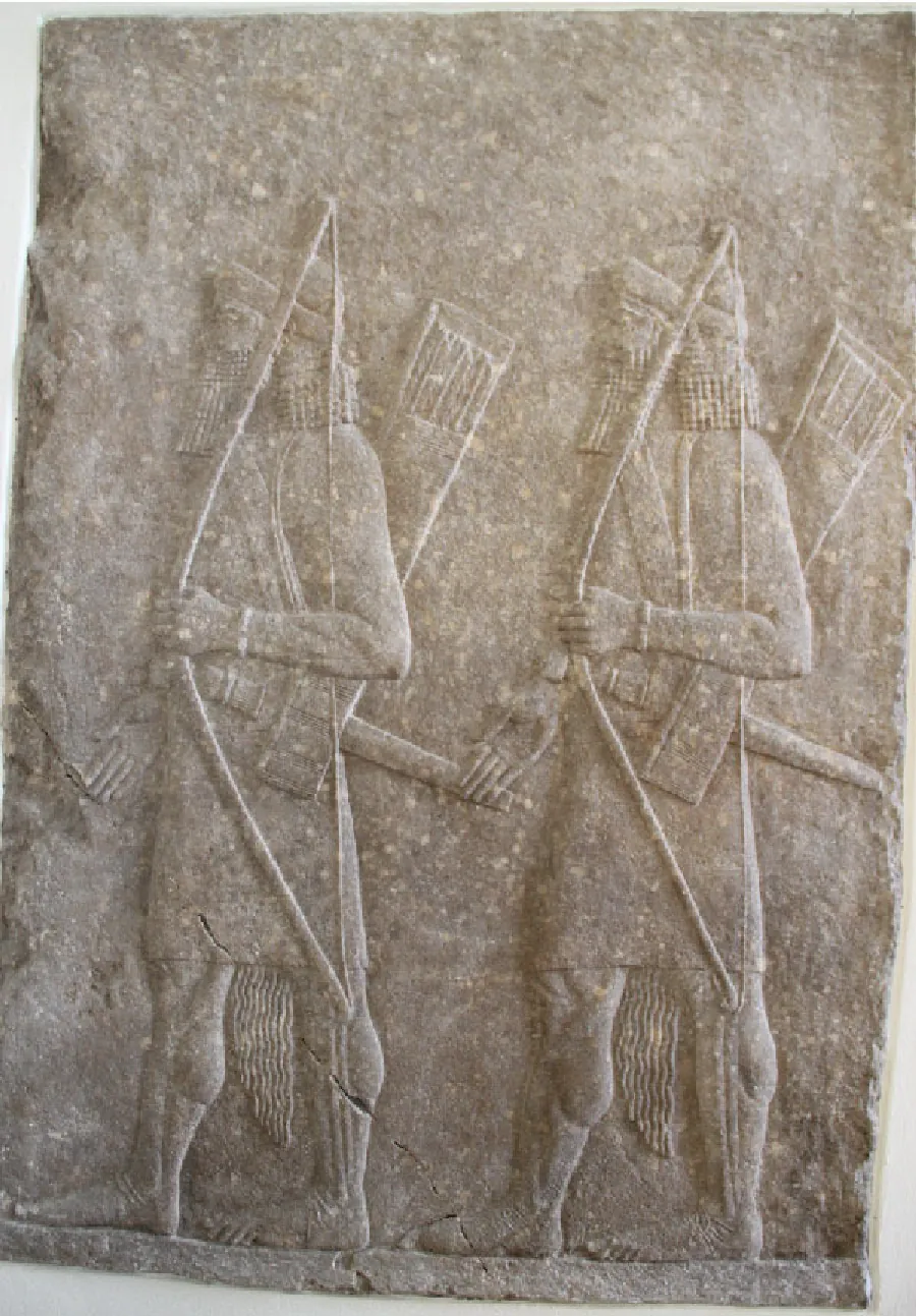 A picture of a stone carving of two almost identical figures is shown on gray stone. Both figures are facing left, wearing rounded helmets with long hair and beards, cloths tied with long sashes around their waists, and barefoot. Both figures carry bows in their left hands, axes at their waists, and quivers on their backs.