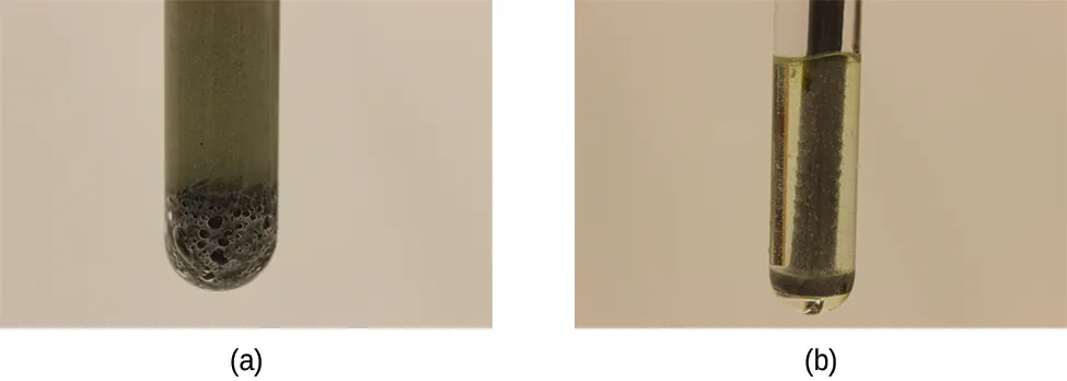 Esta figura muestra dos fotos etiquetadas como (a) y (b). La foto (a) muestra el fondo de un tubo de ensayo. El tubo de ensayo está lleno de un gas oscuro y hay una sustancia oscura y burbujas en el fondo. La foto (b) muestra una varilla y burbujas en un tubo de ensayo similar a la foto (a), pero el gas en el tubo de ensayo no es tan oscuro.