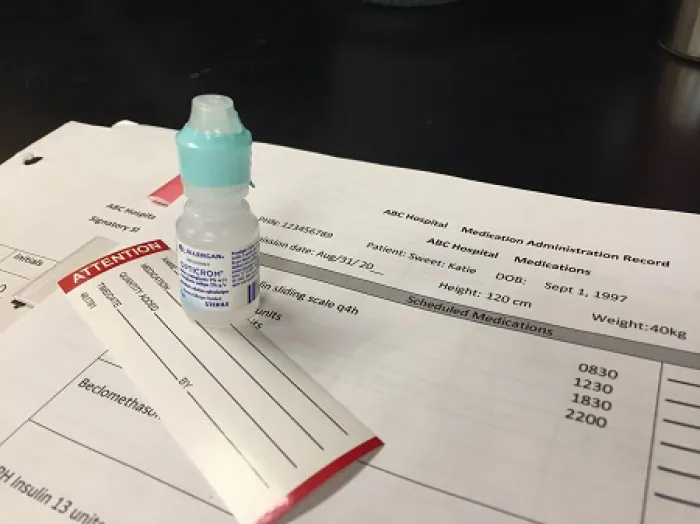 A bottle of eye drops sits on top of a Medication Administration Record.