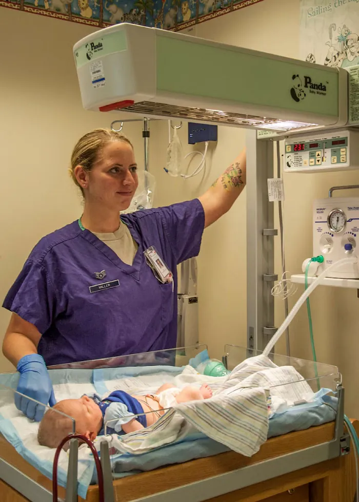 A nurse named Miller gently adjusts the Panda Baby Warmer over a newborn baby, ensuring its comfort and warmth in the hospital nursery.