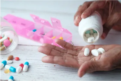 A photograph of a woman’s hands pouring pills from a bottle into her hands for sorting into a daily pill box.