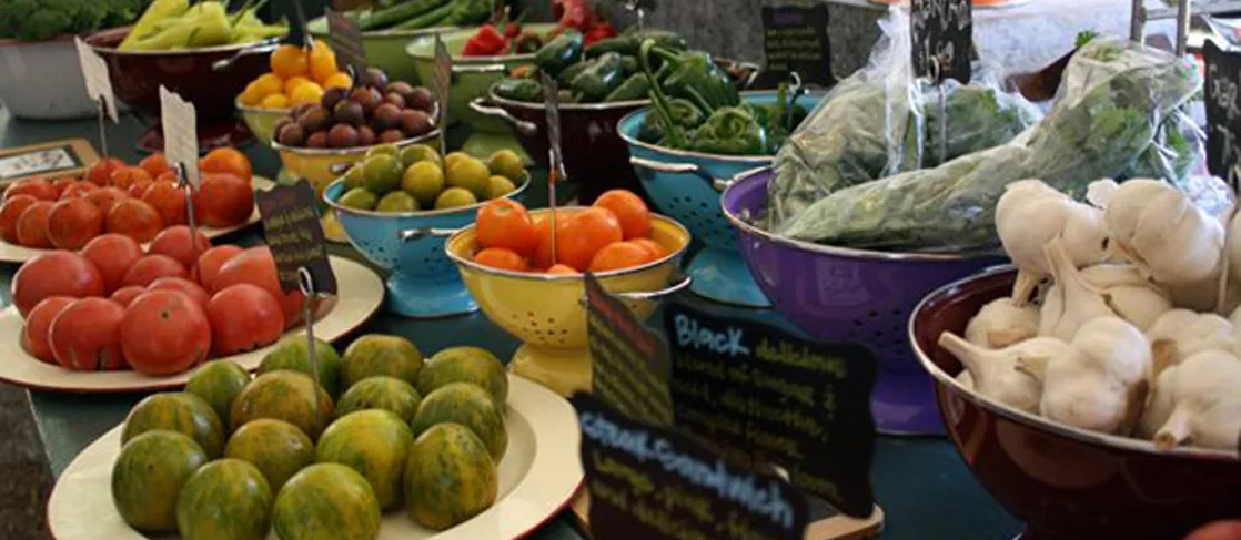 Photo shows a variety of fresh vegetables being sold at a market.