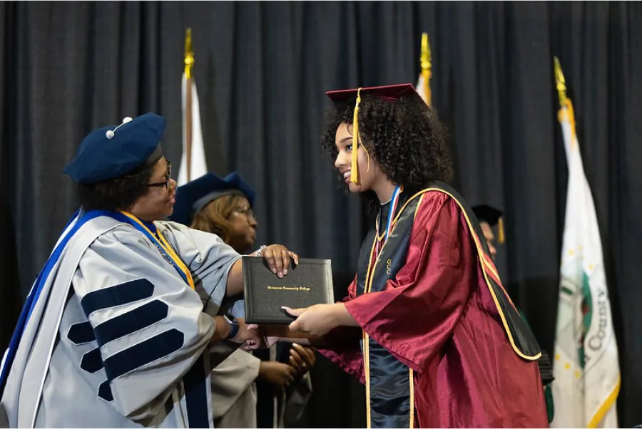 Photo of individual receiving their diploma from a professor at a ceremony.