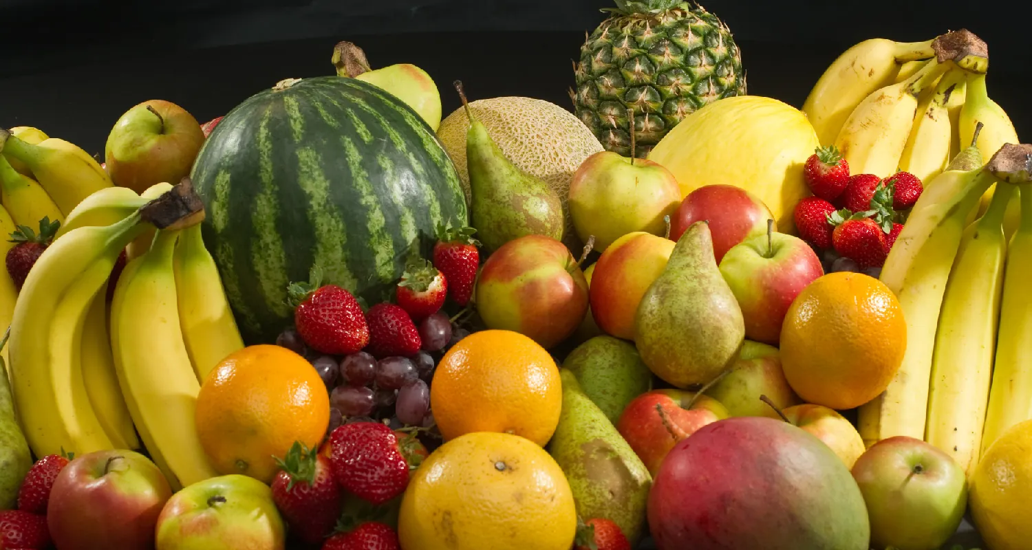 A grouping of fruit includes bunches of bananas, oranges, apples, pears, strawberries, grapes, pineapples, and melons.