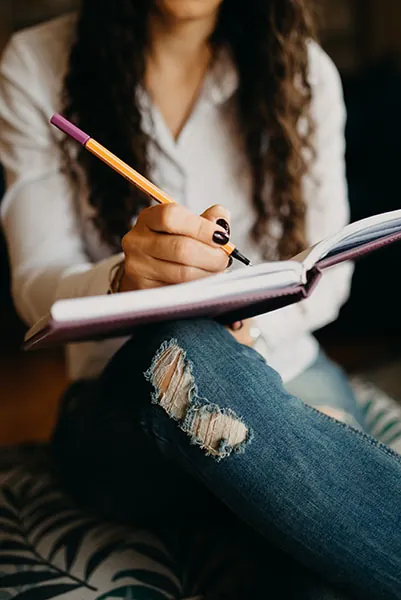 Hands of a woman writing notes in her planner.