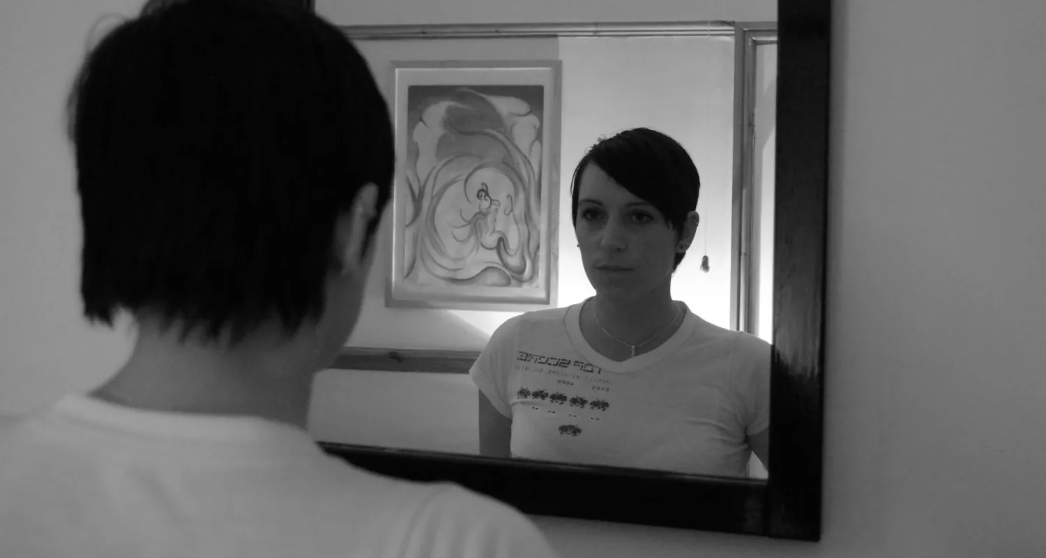 Photo of person looking at themselves in a mirror.