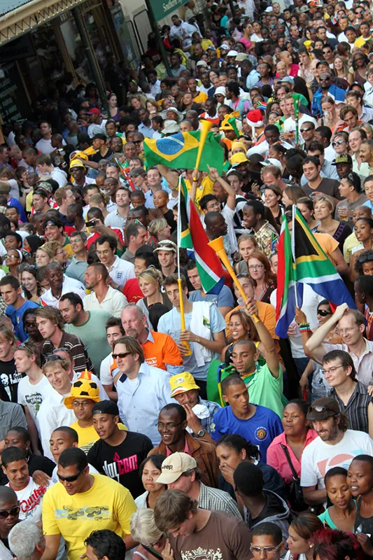 A large crowd of soccer fans waves national flags as they cheer for their teams.