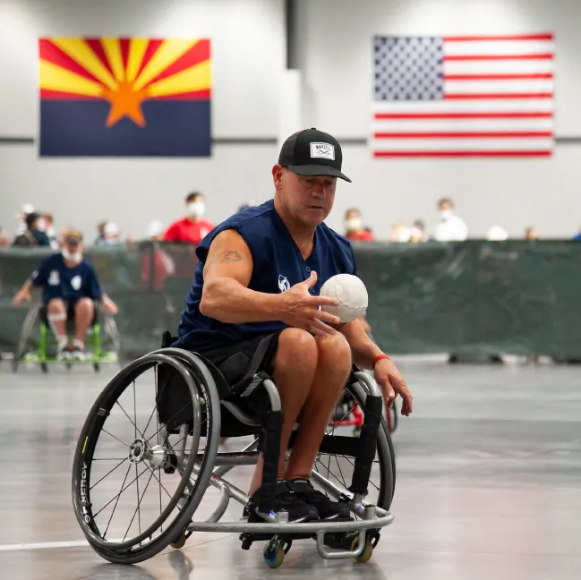 A photograph of a middle-age man playing a sport while in a wheelchair.