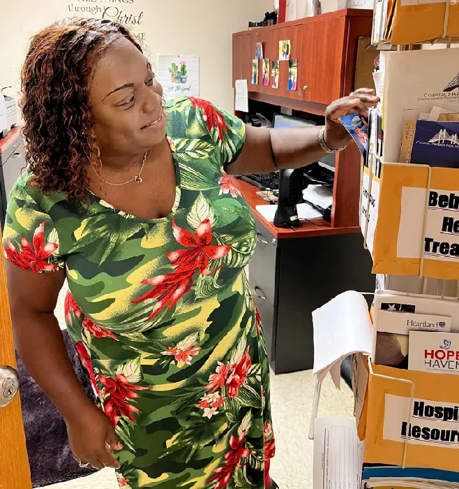 A nurse in an office looks at papers and pamphlets organized in labelled hanging files.