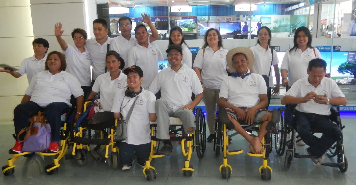 Photo of a group of smiling individuals with back row standing and front row in wheelchairs.