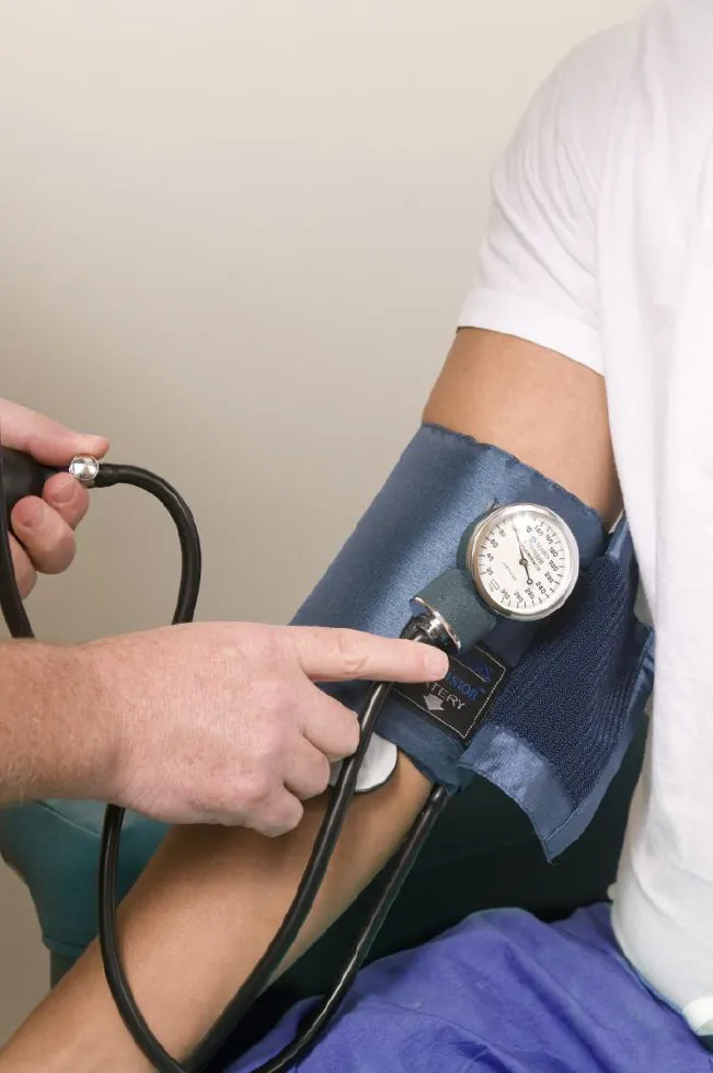 Healthcare professional using blood pressure cuff on patient's arm.