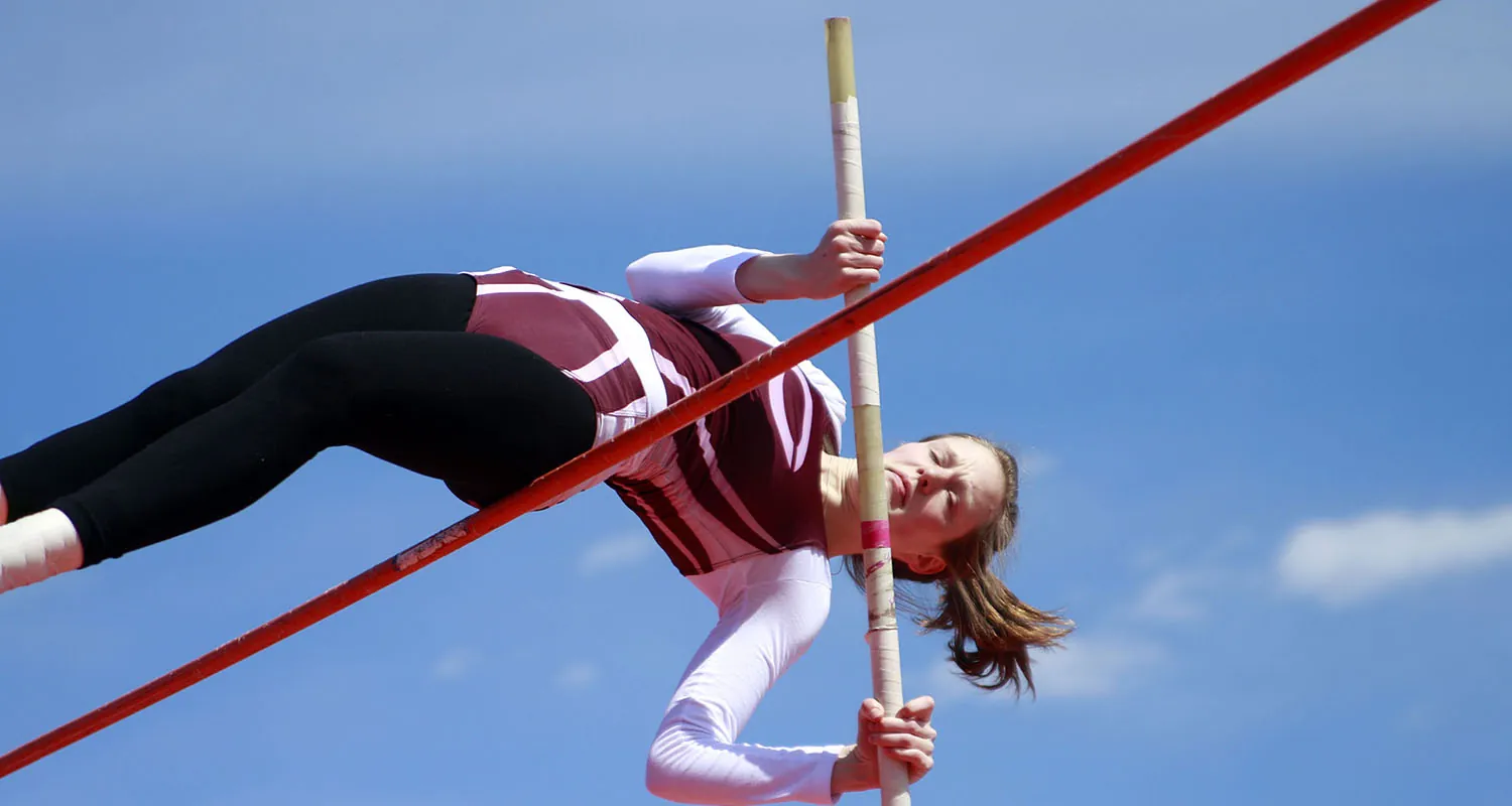 A photo shows a pole vaulter going over the bar.