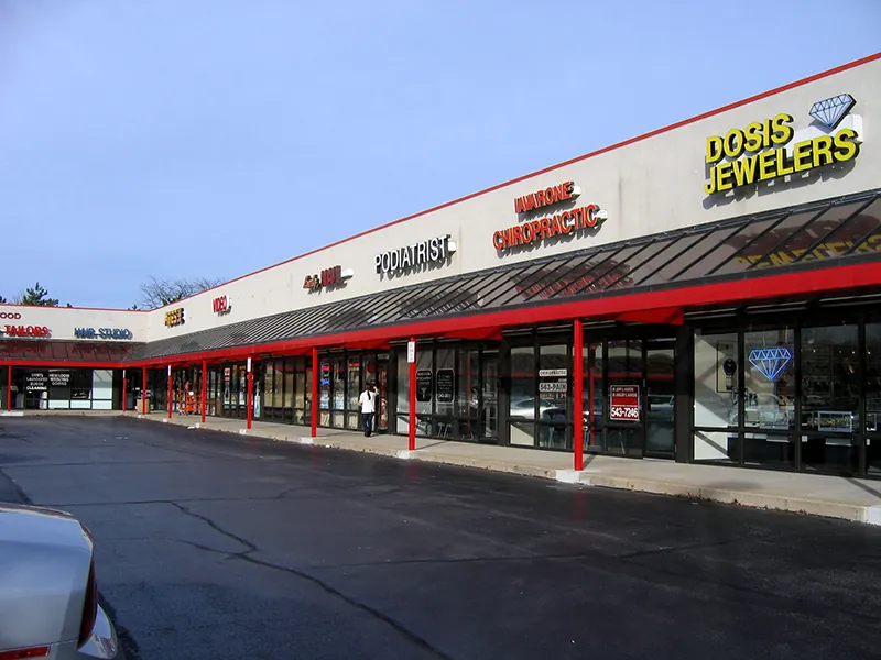 Storefronts are visible from the parking lot. Each storefront takes up about the same amount of space and the store names are placed above an awning.