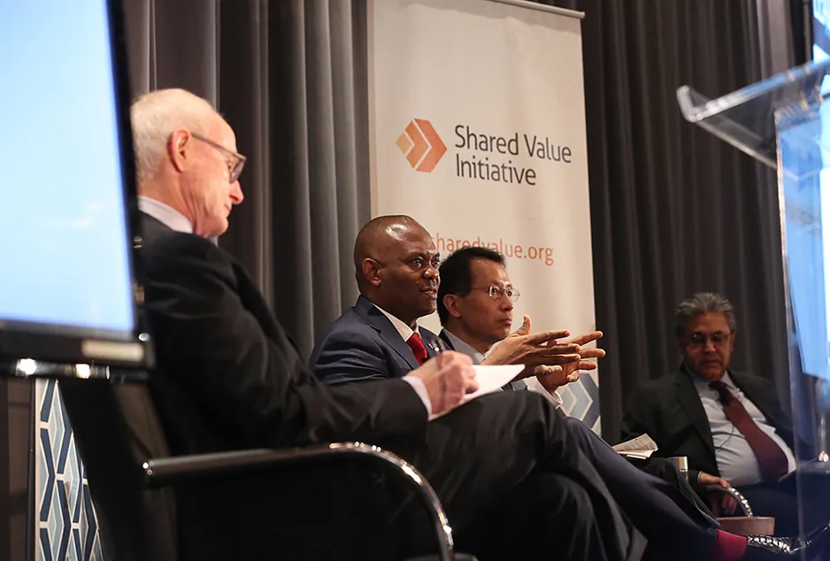 A photo shows Michael E.Porter taking notes during a conversation with Jin-Yong Cai, Tony O. Elurrelu, and Arif Naqvi at the Shared Value Leadership Summit.