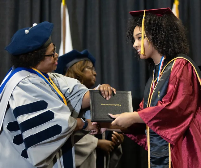 A photograph shows individual in a graduation ceremony.