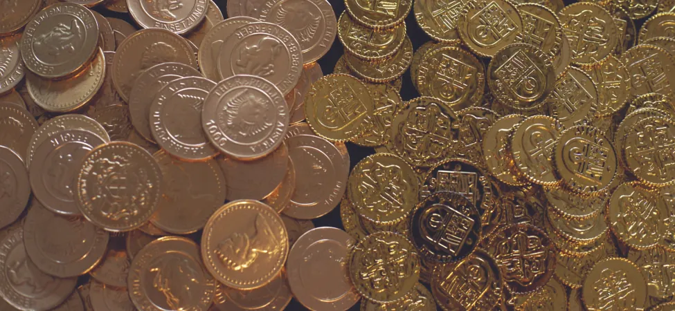 A shimmering bounty of gold coins, divided into two distinct piles, one with intricate Austrian designs and the other with classic treasure chest motifs.