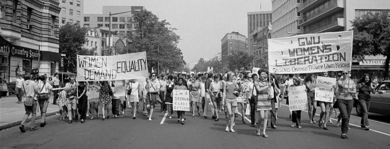 Protesters hold signs ordering equality for women.