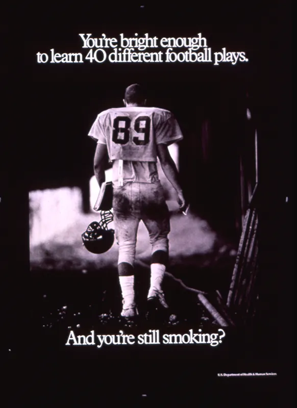 An ad shows the back of a football player in uniform. I his left hand he is holding a football helmet and a notebook. In his right hand he is holding a lit cigarette. The copy on the ad says “You’re bright enough to learn 40 different football plays. And you’re still smoking?”