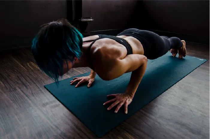 A person holds a plank position on an exercise mat.