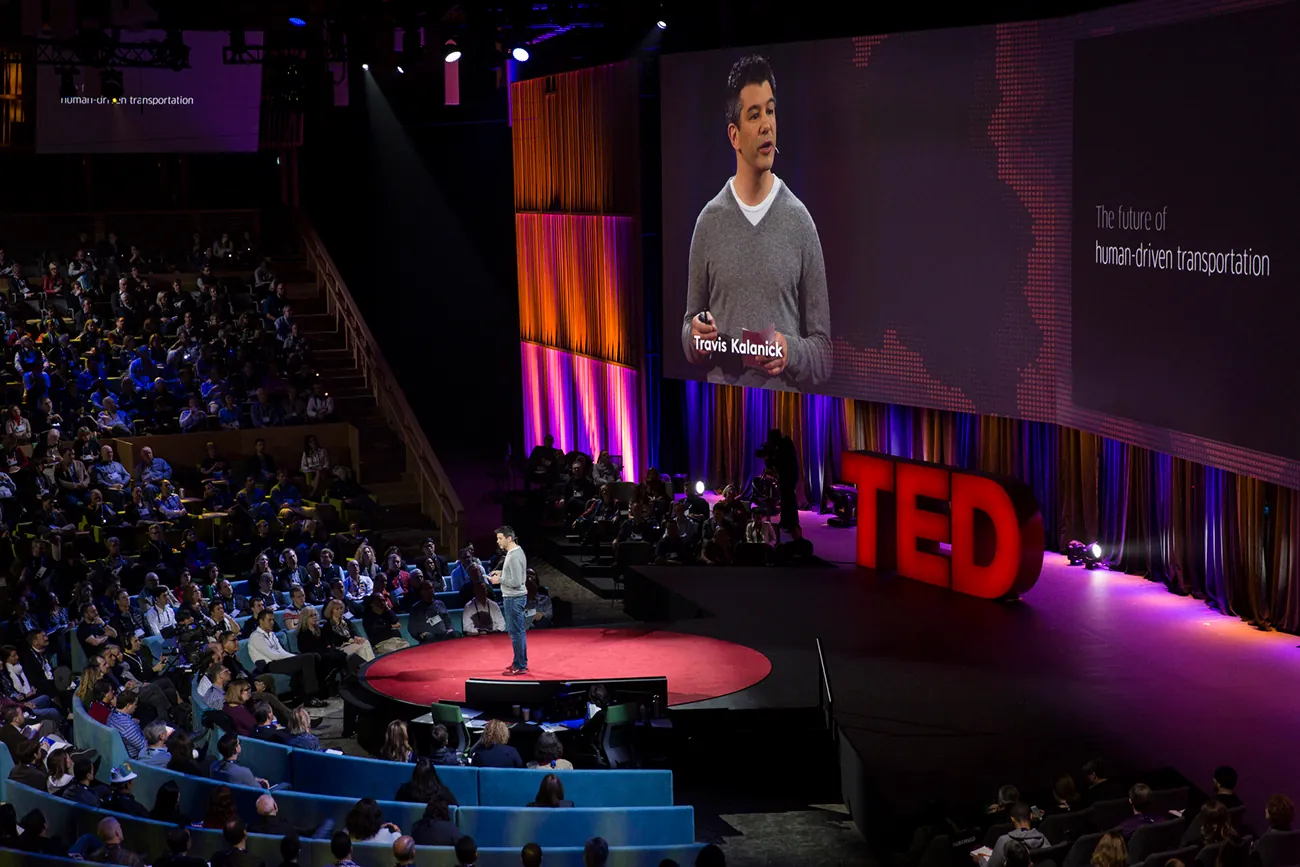 A photo shows Travis Kalanick talking to a large audience during a TED talk.