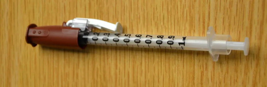 A photograph shows a syringe with a safety shield attached.